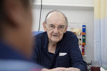 Male patient sitting in a chair on hospital ward