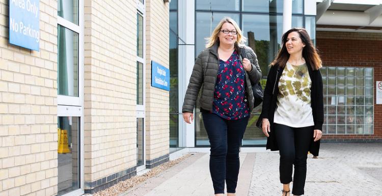 two women walking side by side outside a health centre