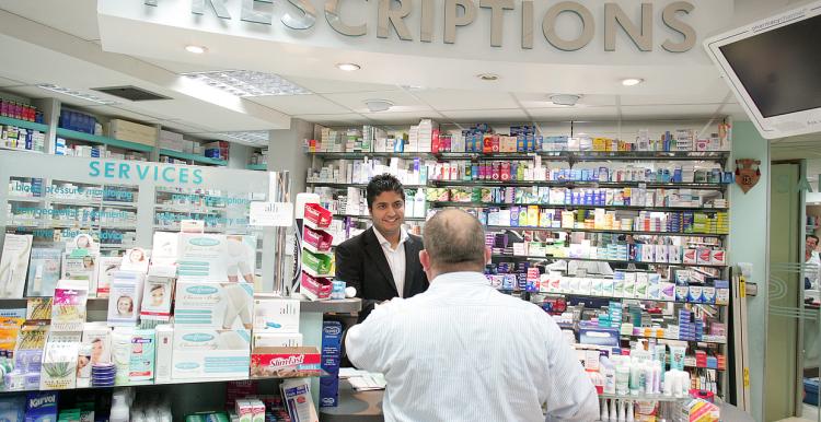 Man getting a prescription from a male pharmacist at a pharmacy counter