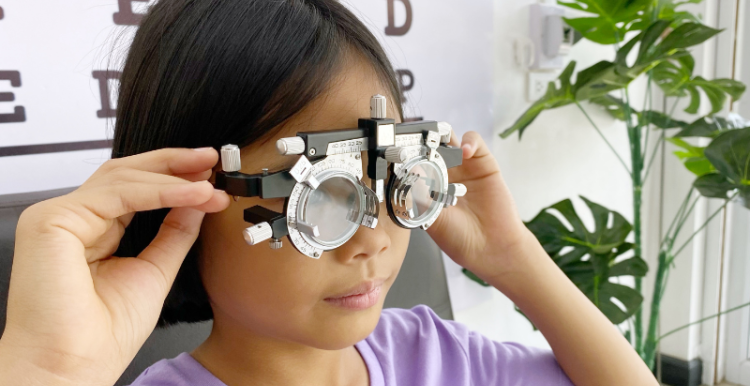 A child looks through eye test lenses. 