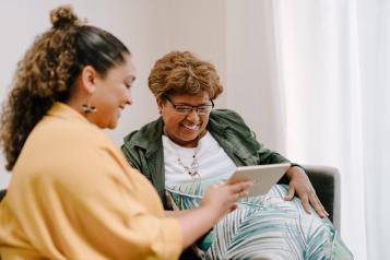 two women socialising looking at an iPad