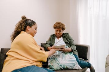 two people sitting on a sofa looking at an iPad