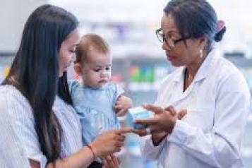 A Pharmacist discusses medication with a woman and baby. 