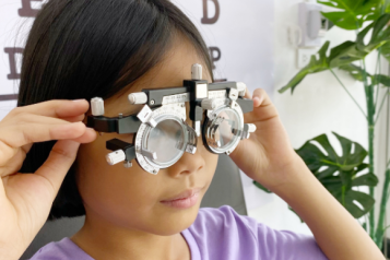 A child looks through eye test lenses. 