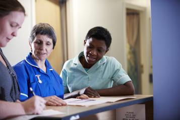 three female medical staff standing by a reception desk