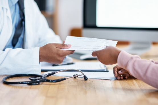 GP handing a note over to a patient