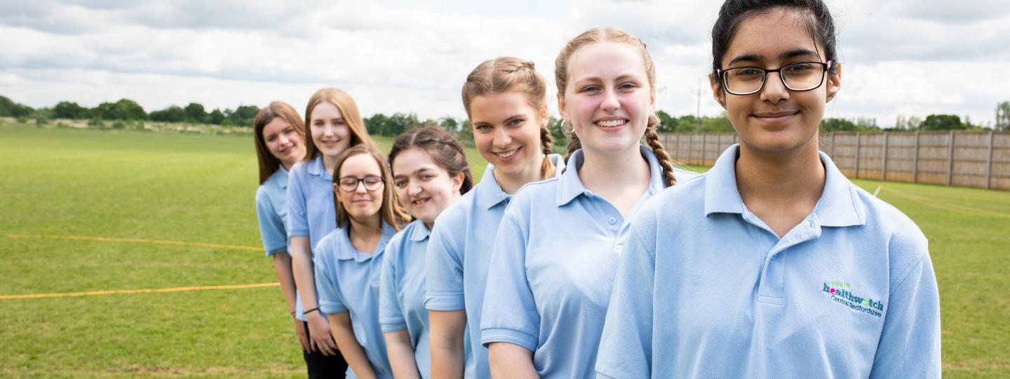 Row of school girls lined up behind each other on the playing field. 