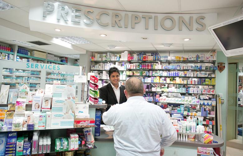 Man getting a prescription from a male pharmacist at a pharmacy counter